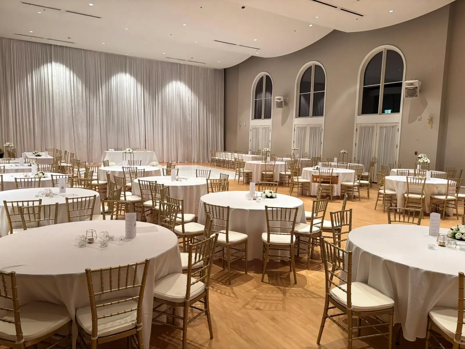 Gold chiavari chairs and white-clothed round tables in a reception hall