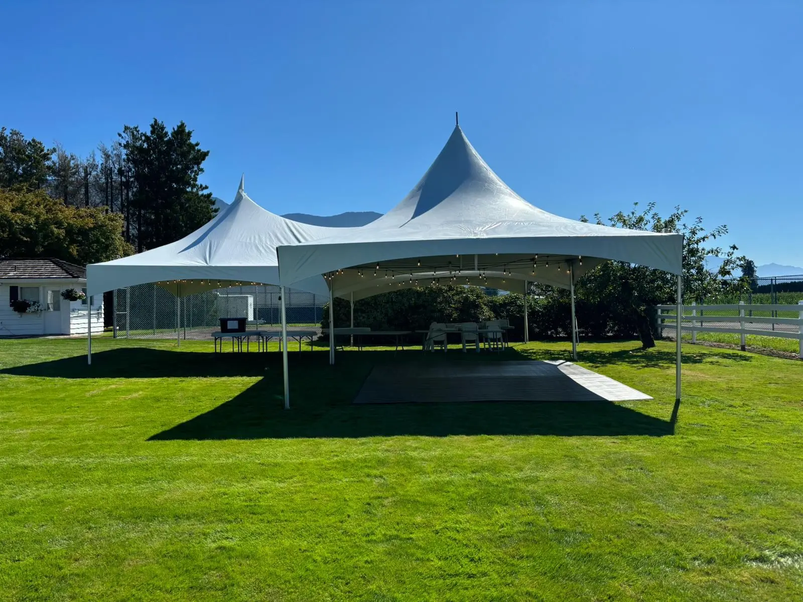 Connected high-peak tents with a dance floor on a green lawn